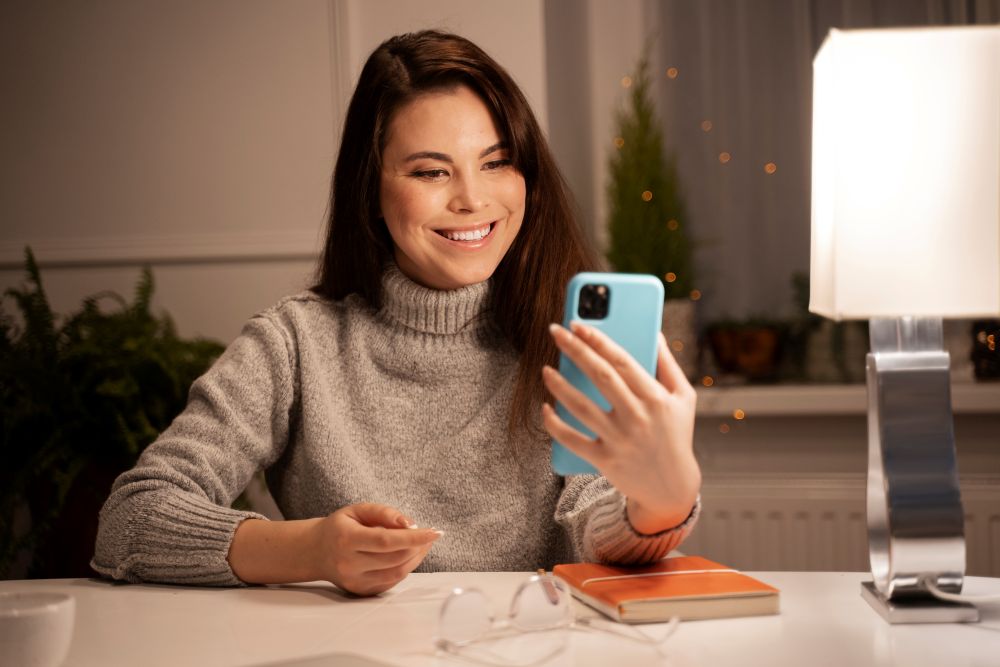 Mulher sorrindo para o celular após realizar sua primeira venda online.