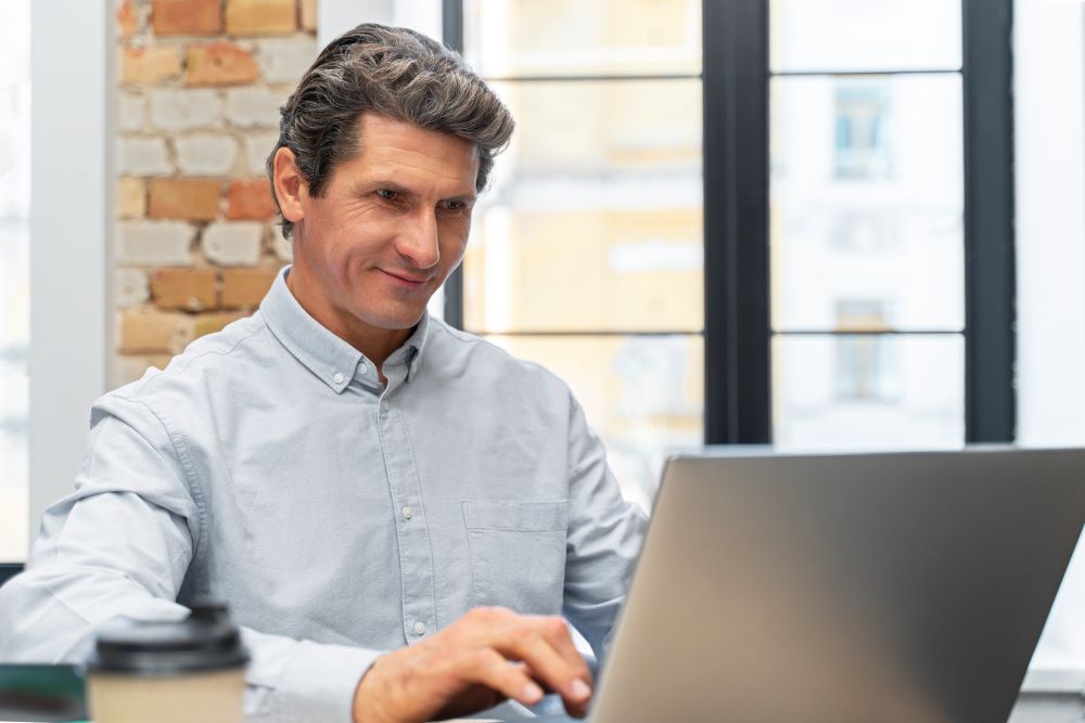 Empresário trabalhando em um laptop, representando dicas de gestão para lojistas e otimização de negócios online.