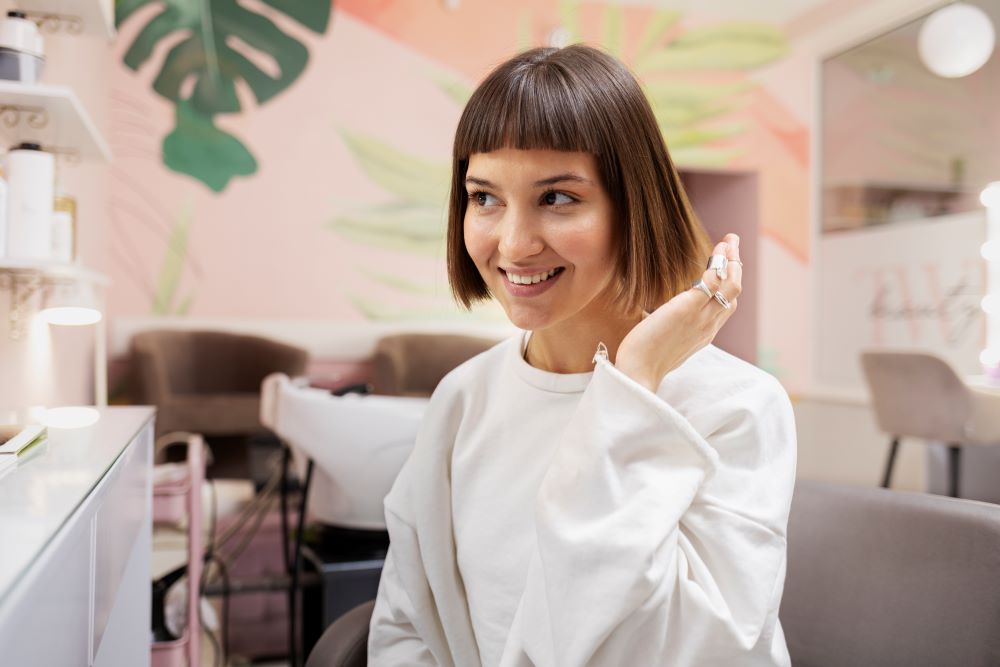 Mulher sorrindo em um salão de beleza moderno, ilustrando as tendências para 2025 no mercado de beleza no Brasil.