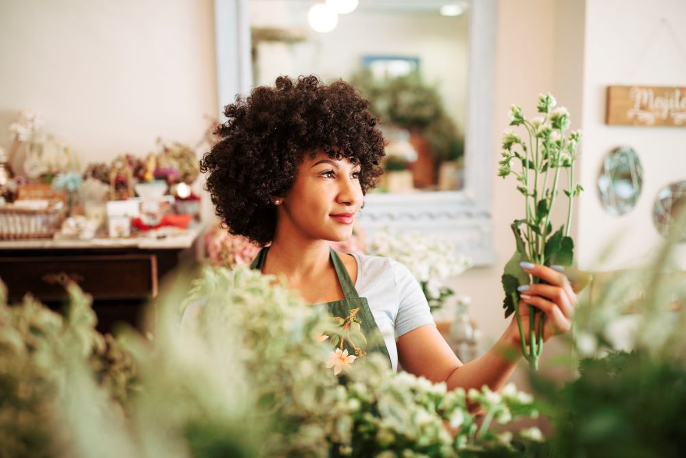 mulher segurando flores em uma loja sustentável, representando o conceito de produtos eco-friendly