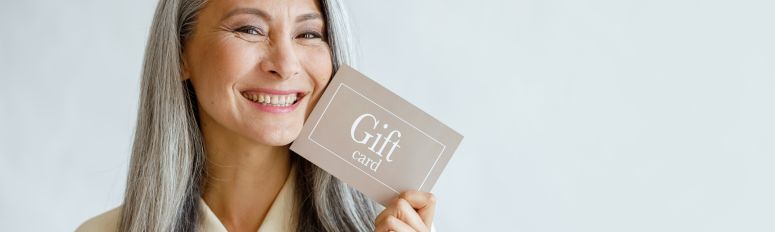 Mulher sorridente segurando um cartão com a palavra 'Gift Card' — exemplo prático para ilustrar o que é gift card.