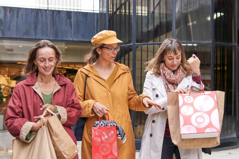 Três mulheres felizes após realizar compras, representando o sucesso de campanhas em sites de compras coletivas que atraem consumidores para ofertas e descontos.