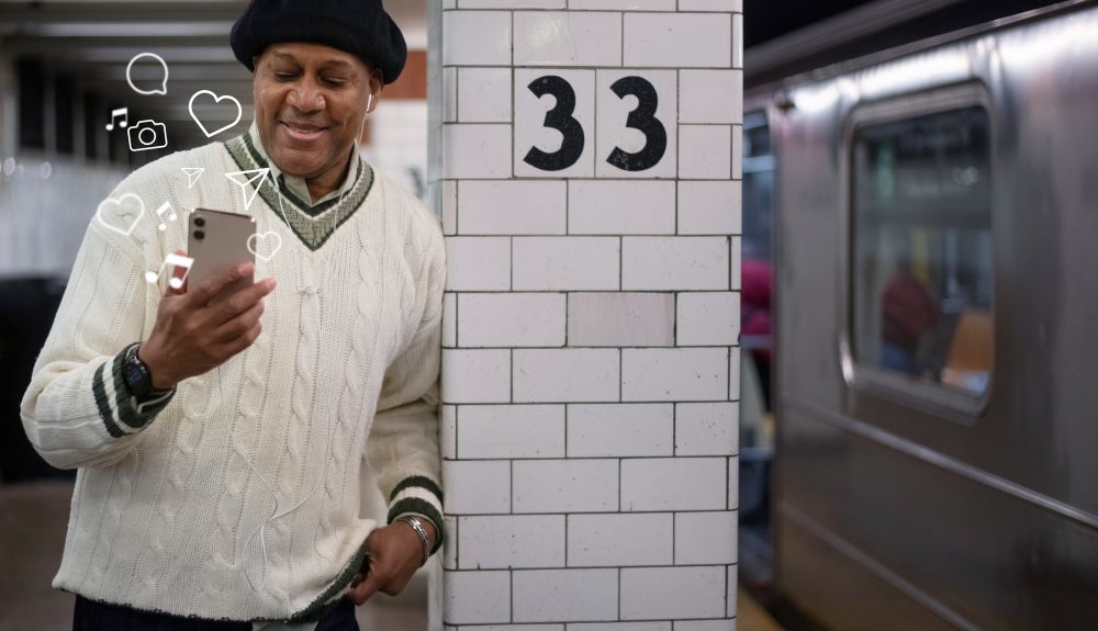 Homem sorrindo ao criar conteúdo no celular com elementos gráficos — exemplo de uso do Symphony Creative Studio para vídeos no TikTok
