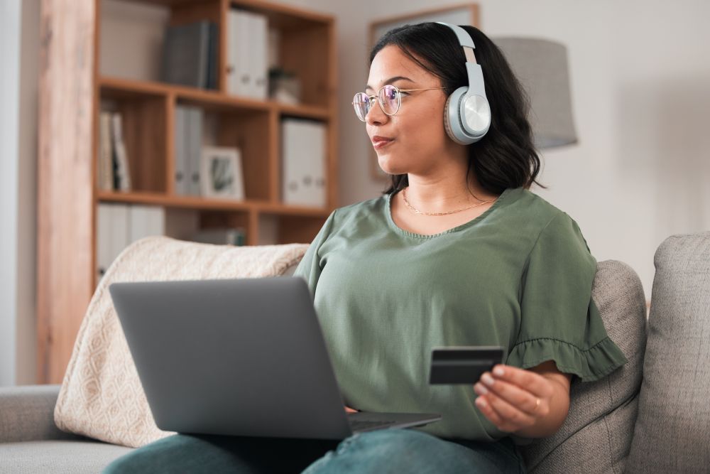 Mulher fazendo compra online com notebook e cartão de crédito, representando o direito do consumidor online.