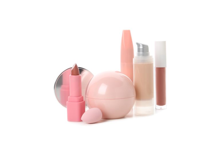 Mix de produtos de beleza com batom, base, gloss e creme facial em tons rosados