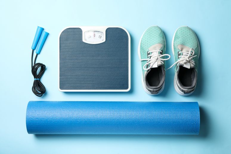 Mix de produtos fitness com tênis esportivos, corda, tapete de yoga e balança.