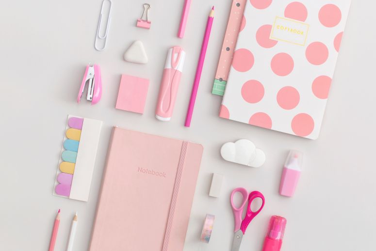 Mix de produtos de papelaria com cadernos, lápis, tesoura e adesivos coloridos.