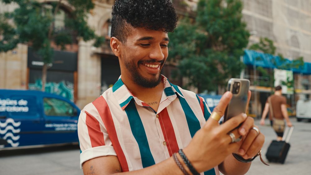 Homem sorrindo enquanto interage com o celular — exemplo de uso criativo das Notas no Instagram para engajar seguidores.
