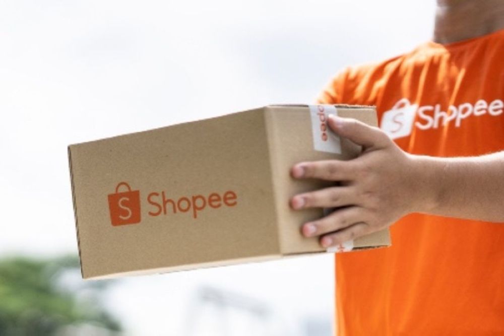 Pessoa com camiseta da Shopee segurando caixa de entrega — representação visual de como ser entregador da Shopee.