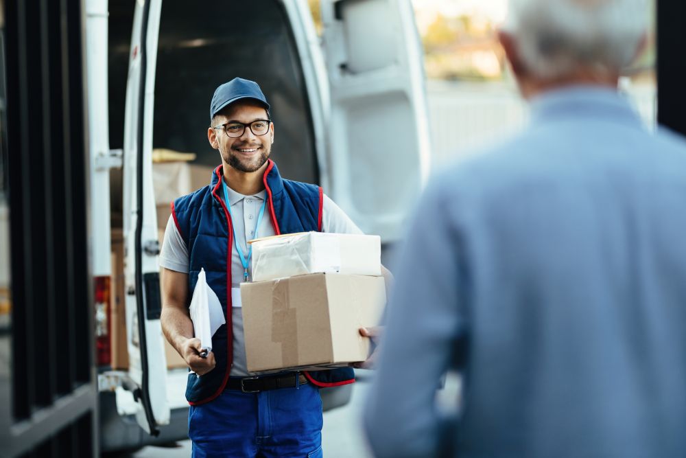 Entregador sorridente realizando entrega de pacotes, ilustrando o processo de como enviar encomenda por transportadora.