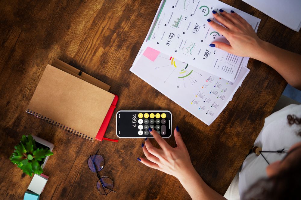 Pessoa analisando gráficos e calculadora para entender como usar relatórios de vendas e planejar promoções mais estratégicas.