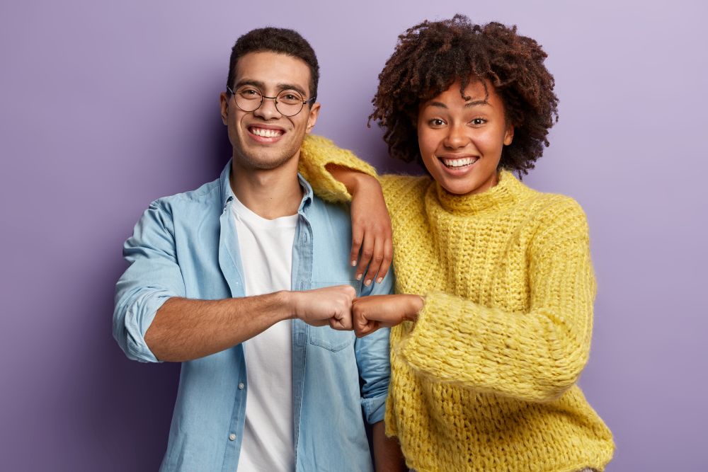 Dois jovens sorridentes cumprimentando-se com toque de punhos, simbolizando parceria e colaboração, representando o programa Parceiro Magalu