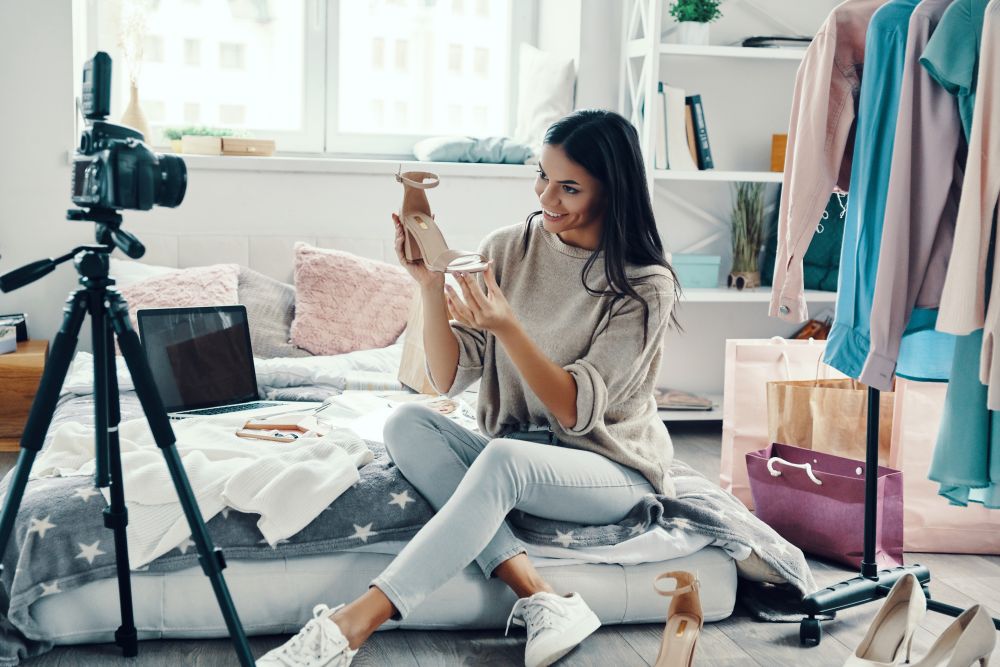 Criadora de conteúdo gravando vídeo sobre moda e calçados, representando vendas e demonstrações de produtos no YouTube Shopping para e-commerce.