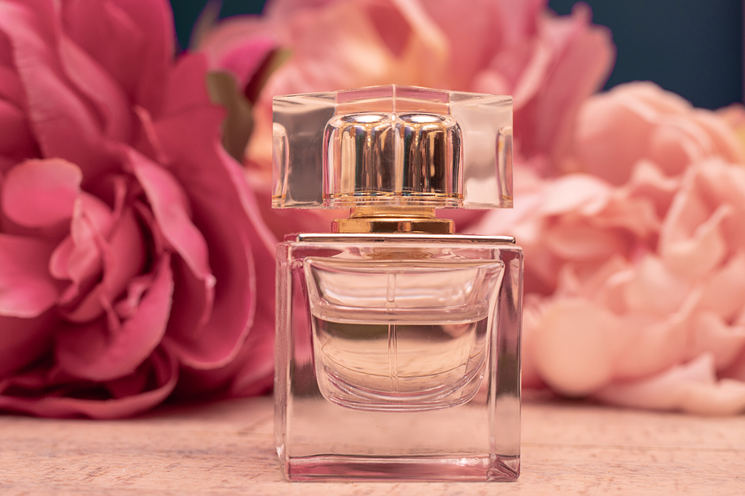 rasco de perfume elegante em destaque, com flores ao fundo, representando produto premium para loja de perfumes e cosméticos.